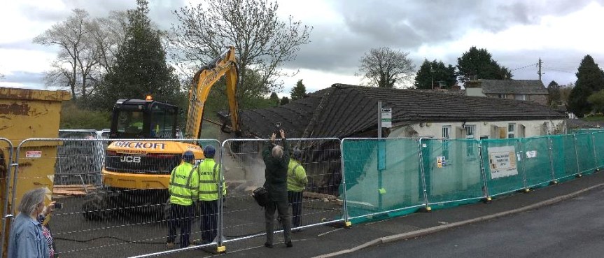 A digger demolishing the original village hall